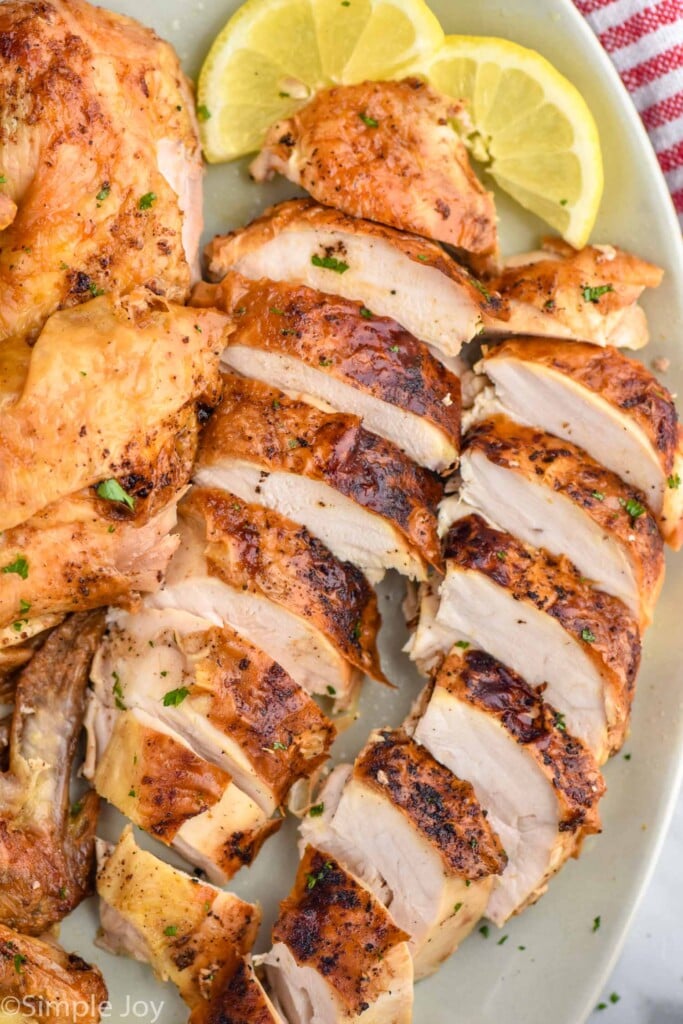 Overhead photo of Air Fryer Whole Chicken sliced and served on a plate with lemon slices.