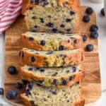 Overhead photo of blueberry banana bread sliced on a wooden cutting board. - 19