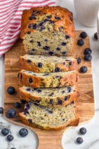 Overhead photo of blueberry banana bread sliced on a wooden cutting board.