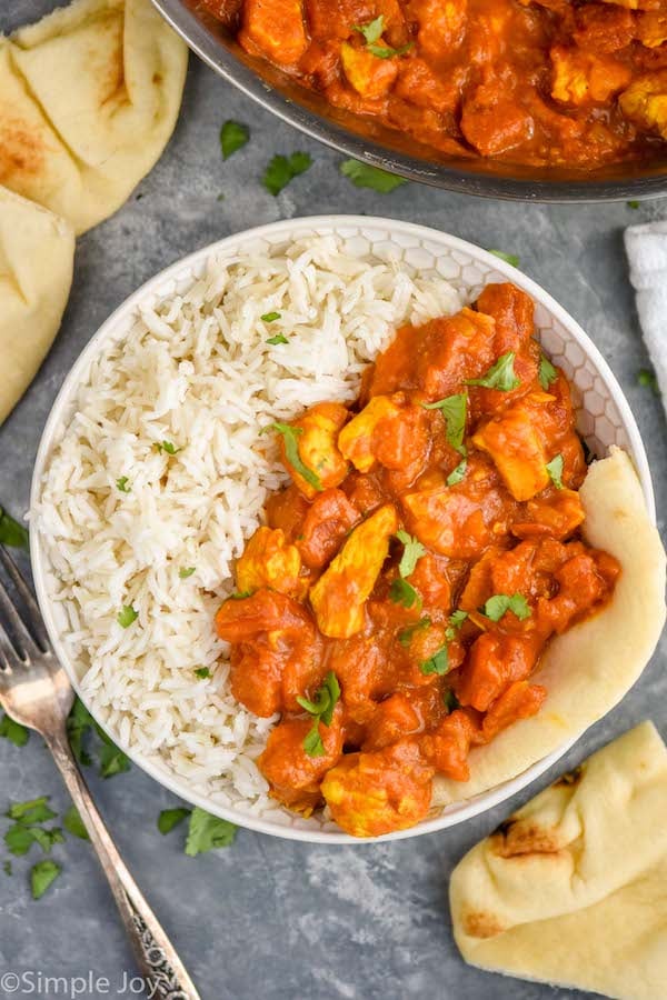 Overhead photo of chicken curry recipe. Bowl of chicken curry, rice, and naan.