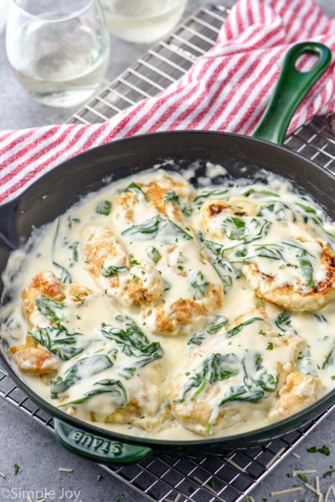 Overhead photo of Chicken Florentine recipe in a skillet with red and white striped towel under the pan.