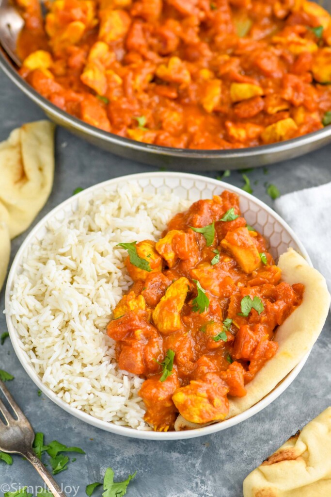 Overhead photo of chicken curry recipe. Bowl of chicken curry, rice, and naan.