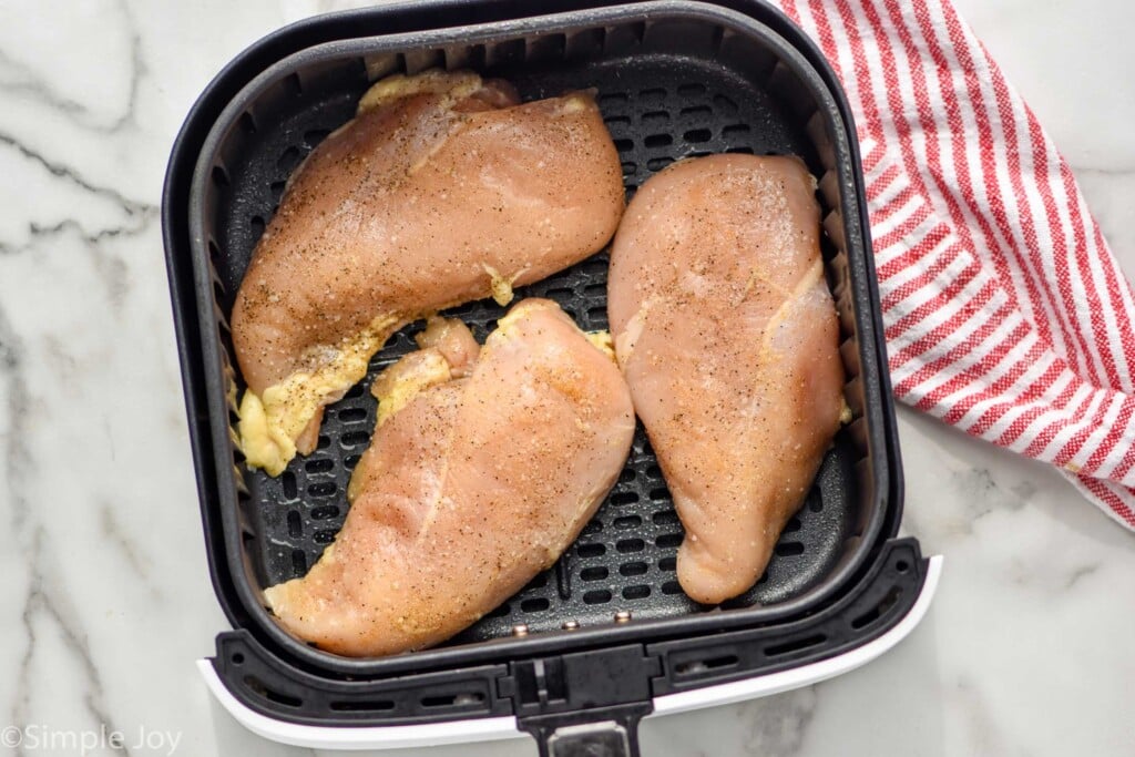 Overhead photo of raw air fryer chicken breasts recipe in air fryer basket