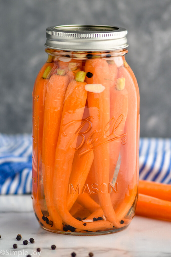 Photo of pickled carrots recipe. Sealed mason jar filled with pickled carrots sitting on countertop.