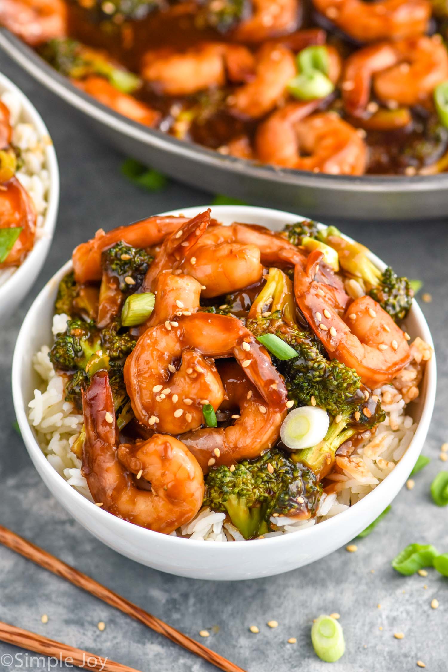 Overhead photo of shrimp and broccoli stir fry in a white bowl served over rice.
