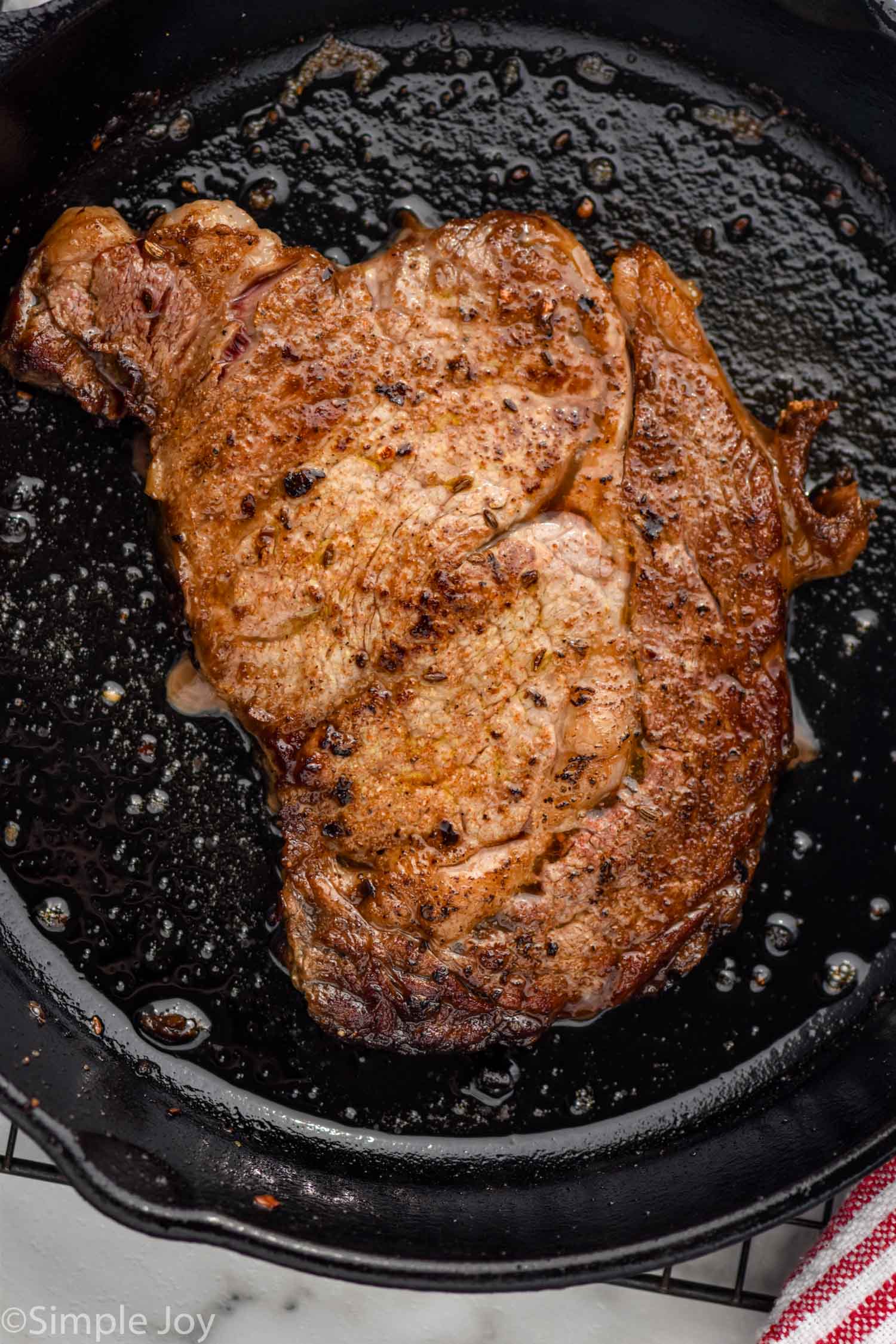 overhead of a steak seasoning recipe on a cooked steak in a cast iron skillet