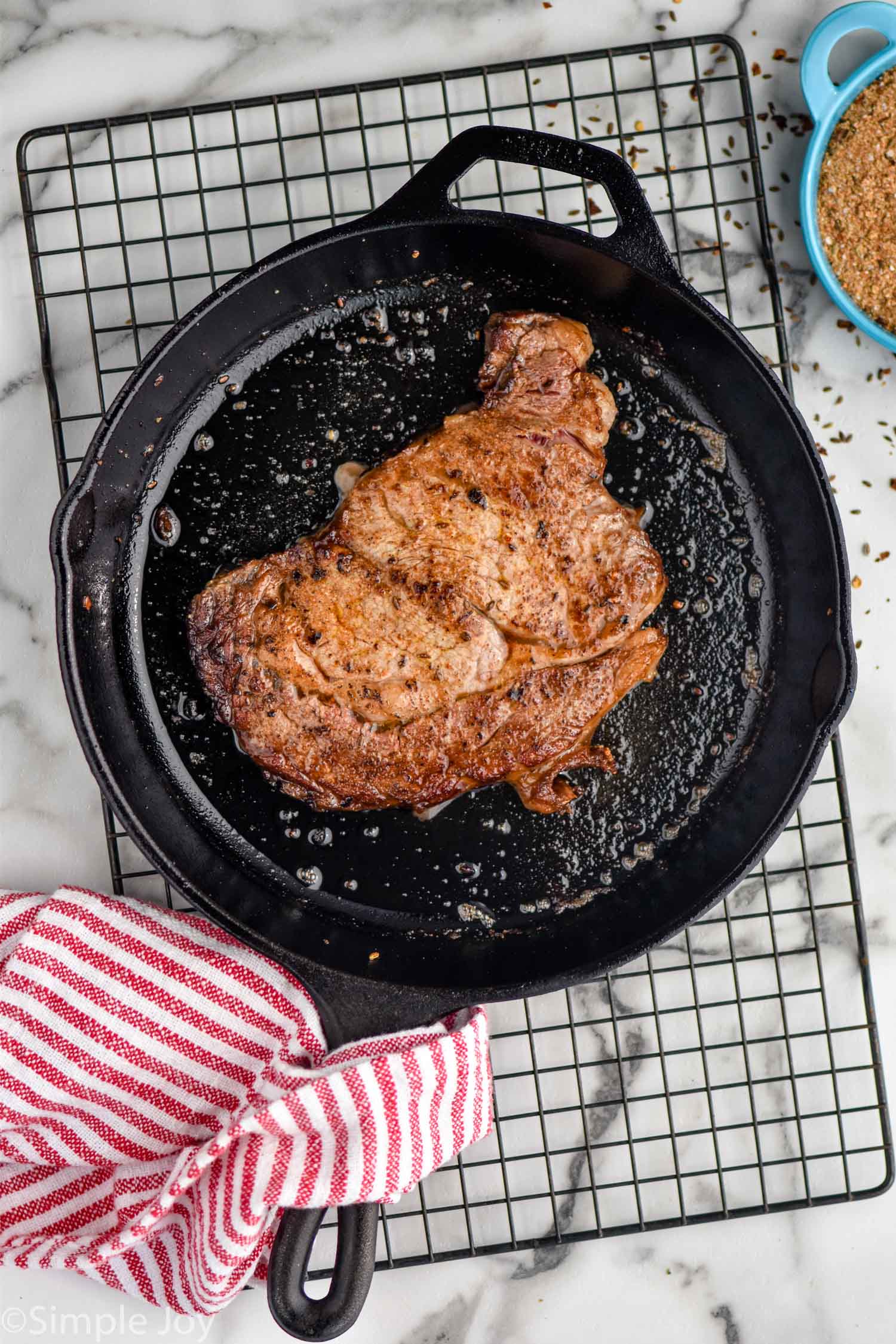 overhead of a steak seasoned with steak seasoning in a cast iron skillet