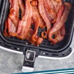 Pinterest graphic of air fryer bacon recipe. Text says, "Air fryer bacon simplejoy.com" Image is an overhead photo of air fryer bacon in an air fryer basket.