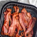Pinterest graphic of air fryer bacon recipe. Text says, "The best air fryer bacon simplejoy.com" Image is an overhead photo of air fryer bacon in an air fryer basket.
