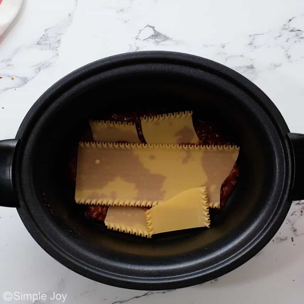 overhead of a crockpot with broken up noodles in it