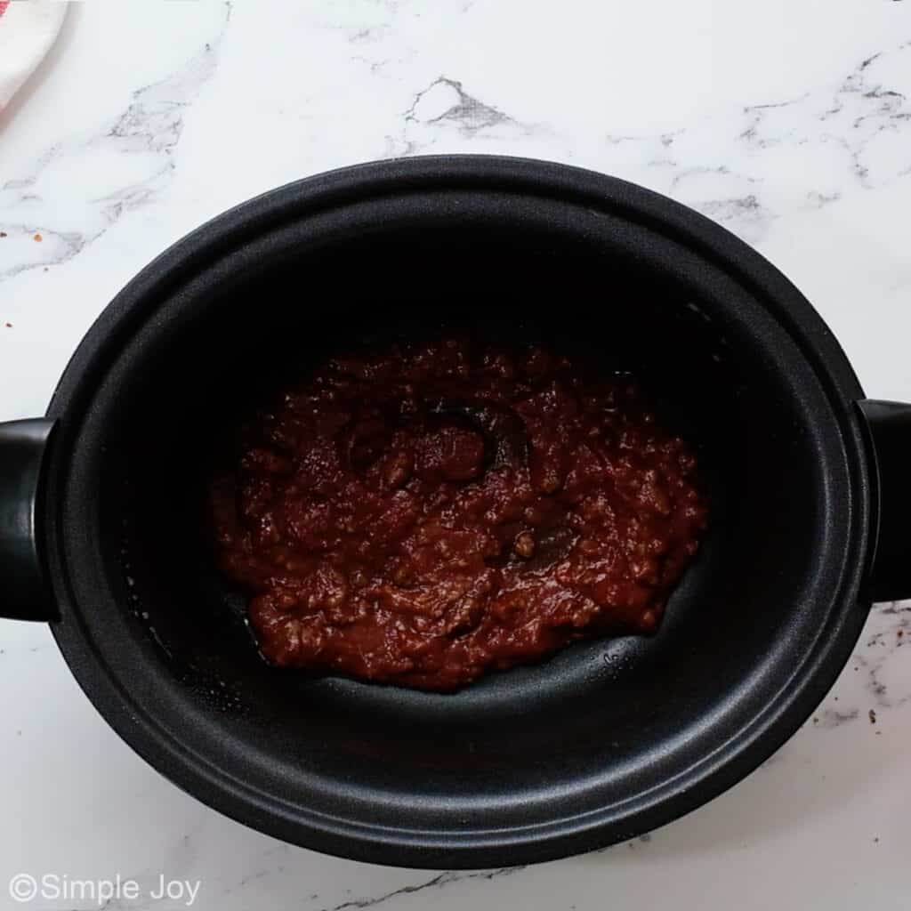 overhead of a crockpot with meat sauce in the bottom