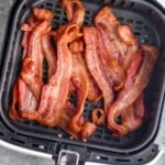 Overhead photo of cooked strips of bacon in air fryer basket for air fryer bacon. - 9