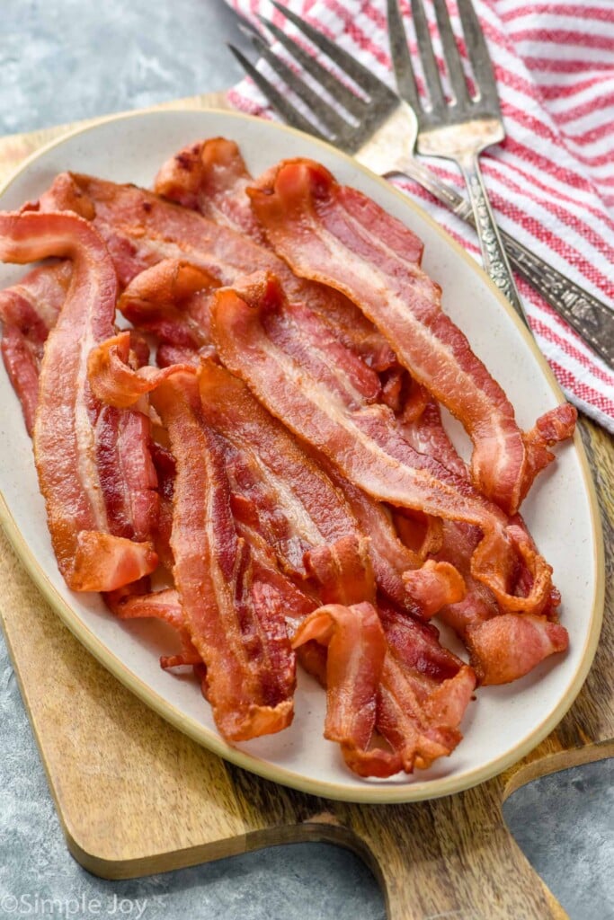 Overhead photo of air fryer bacon served on a plate with a forks for serving.