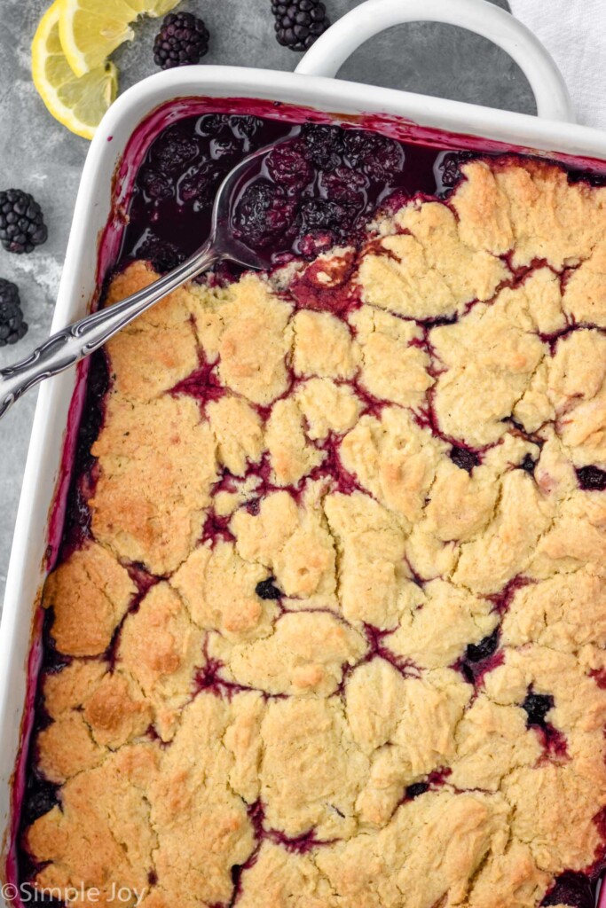 Overhead photo of blackberry cobbler with a spoon scooping out a serving.