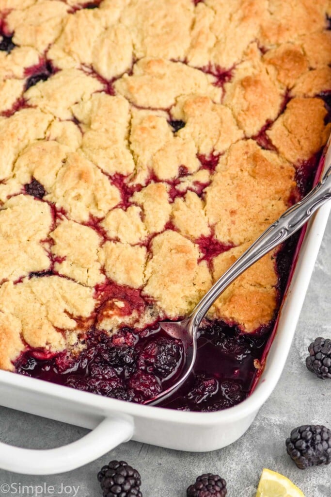 Overhead photo of blackberry cobbler with a spoon scooping out a serving.