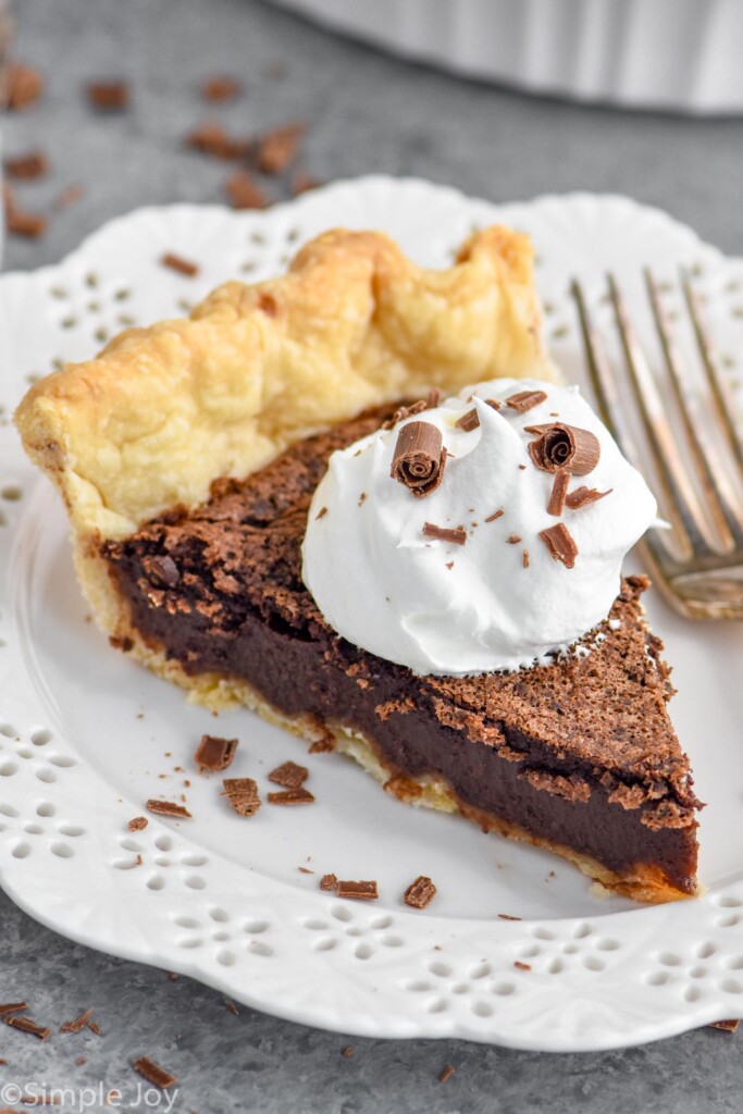 Overhead photo of slice of chocolate chess pie garnished with a dollop of whipped cream. Slice is served in a plate with a fork.