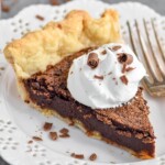 Overhead photo of slice of chocolate chess pie garnished with a dollop of whipped cream. Slice is served in a plate with a fork. - 8