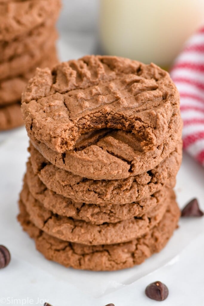 Overhead photo of a stack of chocolate peanut butter cookies. Top cookie has a bite taken out of it.