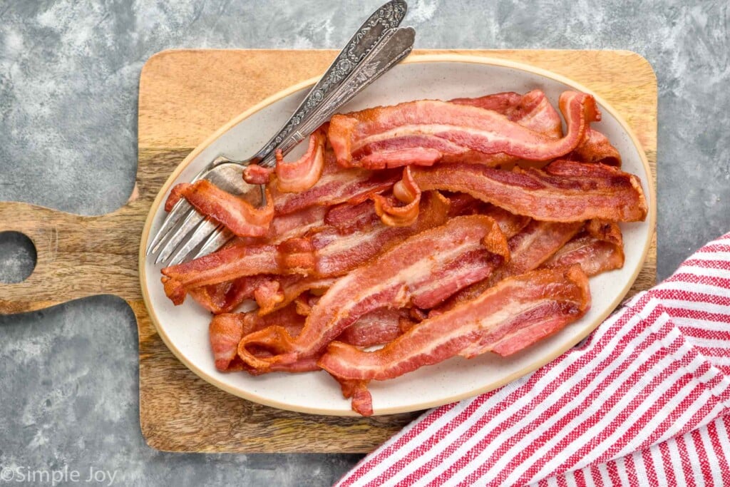 Overhead photo of air fryer bacon served on a plate with a forks for serving.