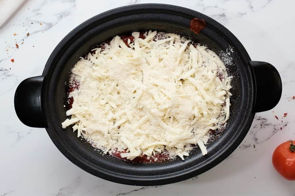a crockpot lasagna with cheese on top ready to be cooked