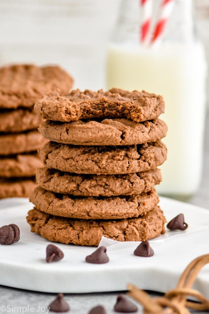 Overhead photo of a stack of chocolate peanut butter cookies. Top cookie has a bite taken out of it.