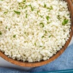 Pinterest graphic of cauliflower rice recipe. Image is overhead photo of cauliflower rice in a bowl for serving. Text says, "How to make: cauliflower rice simplejoy.com."