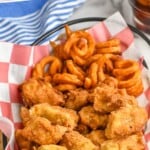 Pinterest graphic for chicken nuggets recipe. Text says, "The best chicken nuggets simplejoy.com." Image is overhead photo of a basket of chicken nuggets and curly fries.