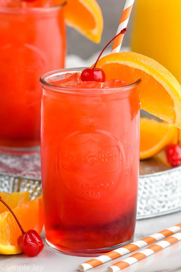 Photo of Alabama Slammer cocktails served in a glass garnished with orange slice and a cherry.