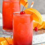 Photo of Alabama Slammer cocktails served in a glass garnished with orange slice and a cherry.
