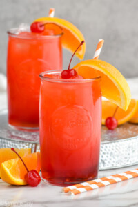 Photo of Alabama Slammer cocktails served in a glass garnished with orange slice and a cherry.