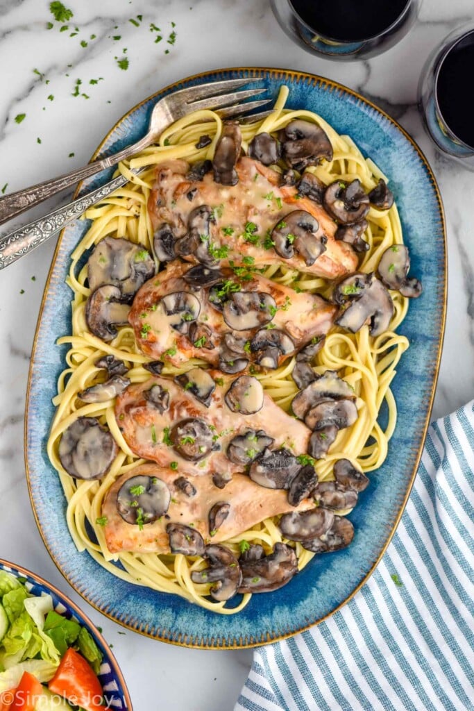 Overhead photo of Crock Pot Chicken Marsala served on a plate of fettuccine pasta.