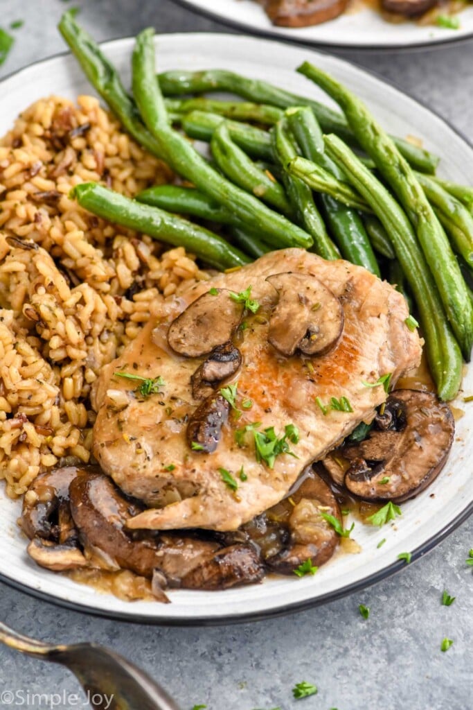 Overhead photo of crock pot pork chops recipe served on a plate with green beans and rice.