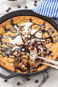 Overhead photo of Pizookie recipe garnished with ice cream and hot fudge sauce. Two forks are in the pizookie for eating.