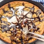 Overhead photo of Pizookie recipe garnished with ice cream and hot fudge sauce. Two forks are in the pizookie for eating.