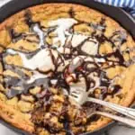 Overhead photo of Pizookie recipe garnished with ice cream and hot fudge sauce. Two forks are in the pizookie for eating.