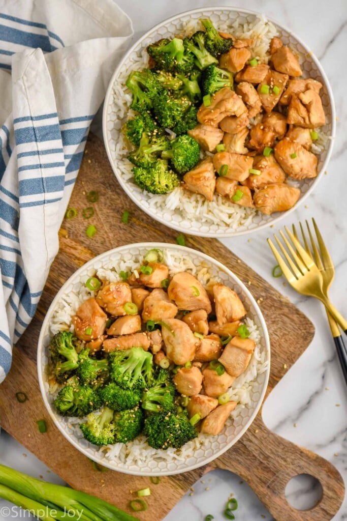 Overhead photo of two plates of teriyaki chicken bowl served with broccoli over rice and two forks for eating.