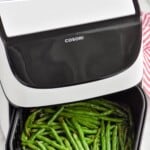 Pinterest graphic for Air Fryer Green Beans recipe. Text says, "Air Fryer Green Beans Recipe simplejoy.com." Overhead photo of Air Fryer Green Beans in an air fryer basket.