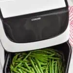 Pinterest graphic for Air Fryer Green Beans recipe. Text says, "Air Fryer Green Beans Recipe simplejoy.com." Overhead photo of Air Fryer Green Beans in an air fryer basket.