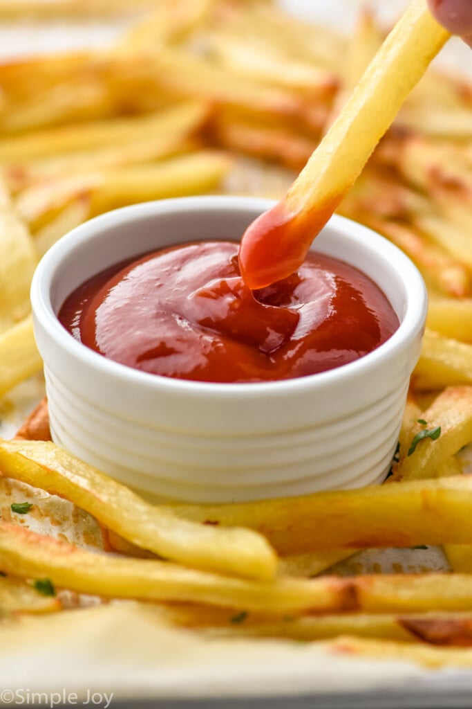 Overhead photo of Easy French Fries with one french fry being dipped in ketchup.