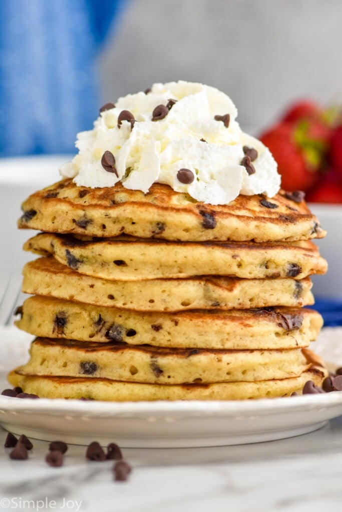 Photo of a stack of Chocolate Chip Pancakes garnished with whipped cream and extra chocolate chips.
