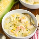 Overhead photo of a bowl of Shrimp and Corn Chowder. Ear of corn beside the bowl as well as a spoon.