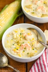 Overhead photo of a bowl of Shrimp and Corn Chowder. Ear of corn beside the bowl as well as a spoon.