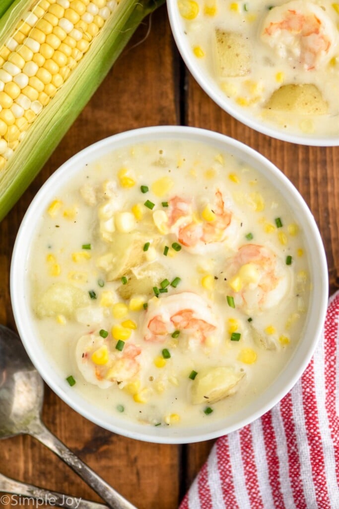 Overhead photo of a bowl of Shrimp and Corn Chowder. Ear of corn beside the bowl as well as a spoon.