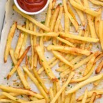 Overhead photo of Easy French Fries on a baking sheet with a dish of ketchup for dipping.