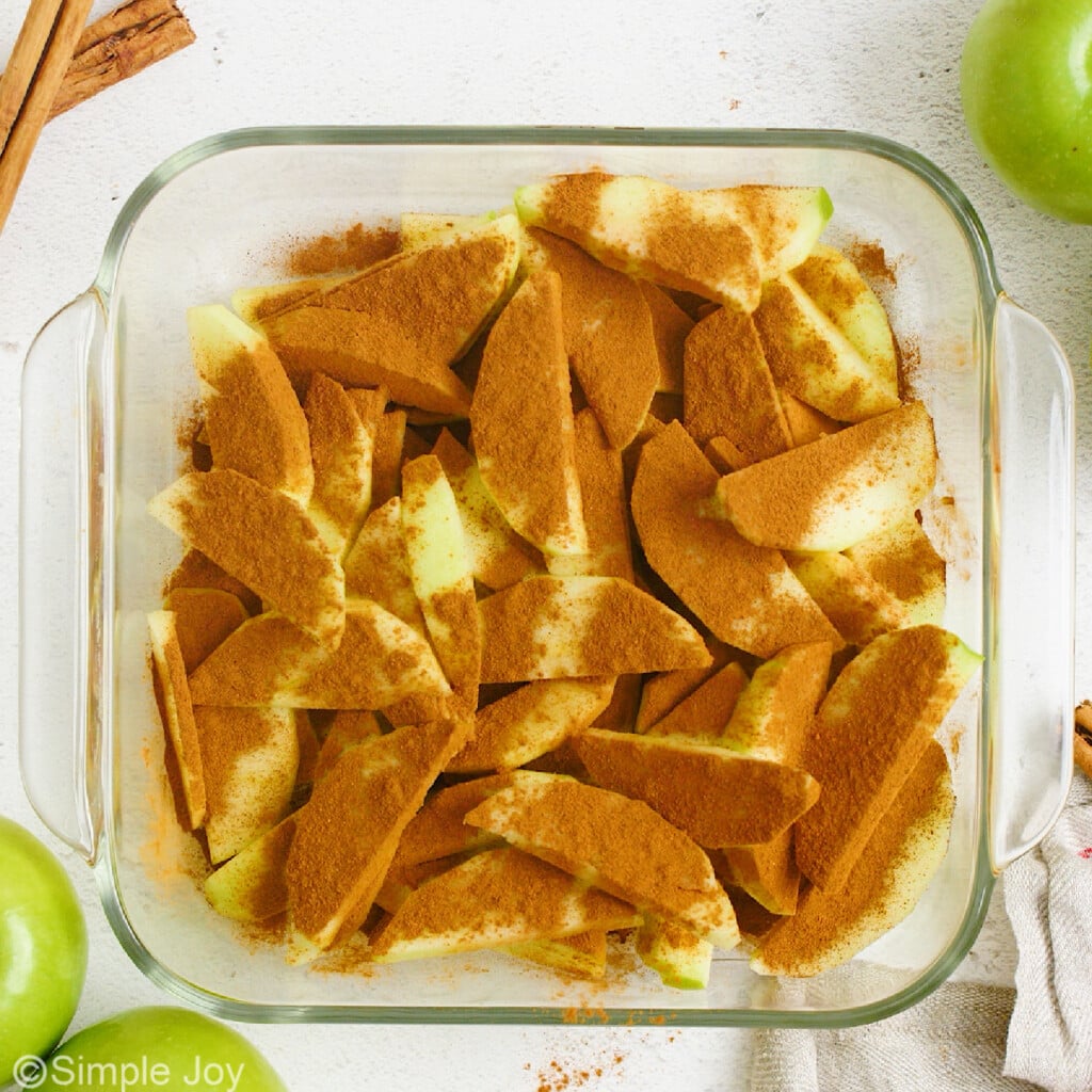 ground cinnamon over apple slices in a casserole dish