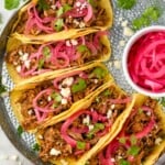 Overhead photo of Pulled Pork Tacos served with pickled red onion and garnished with cilantro.