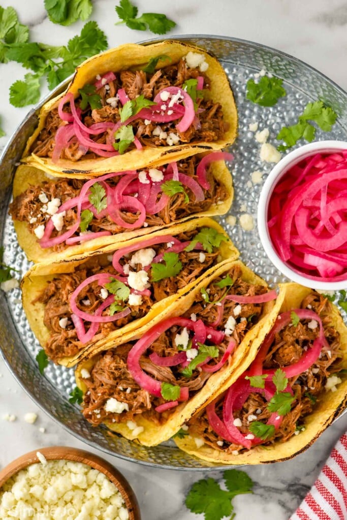 Overhead photo of Pulled Pork Tacos served with pickled red onion and garnished with cilantro.