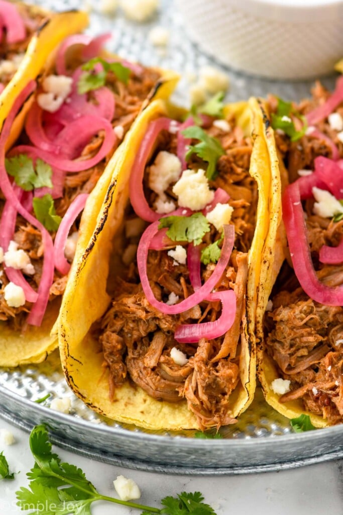 Overhead photo of Pulled Pork Tacos served with pickled red onion and garnished with cilantro.