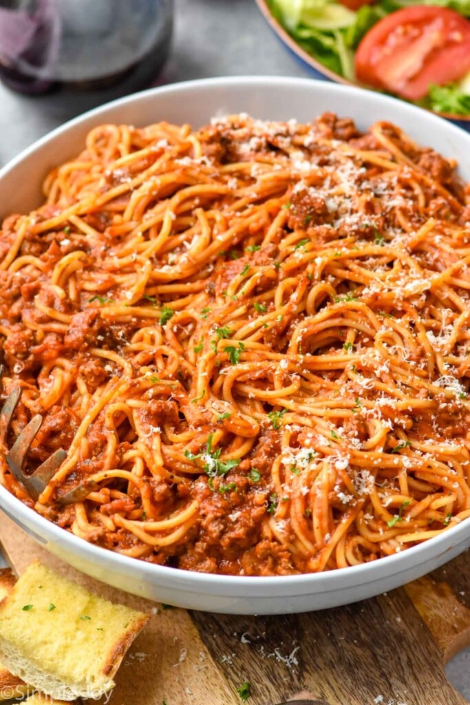 Overhead photo of Crock Pot Spaghetti recipe served in a bowl with parmesan cheese.