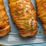 Pinterest graphic for Hasselback potatoes. Text says "Hasselback potatoes simplejoy.com" Image shows overhead of hasselback potatoes garnished and ready for serving.